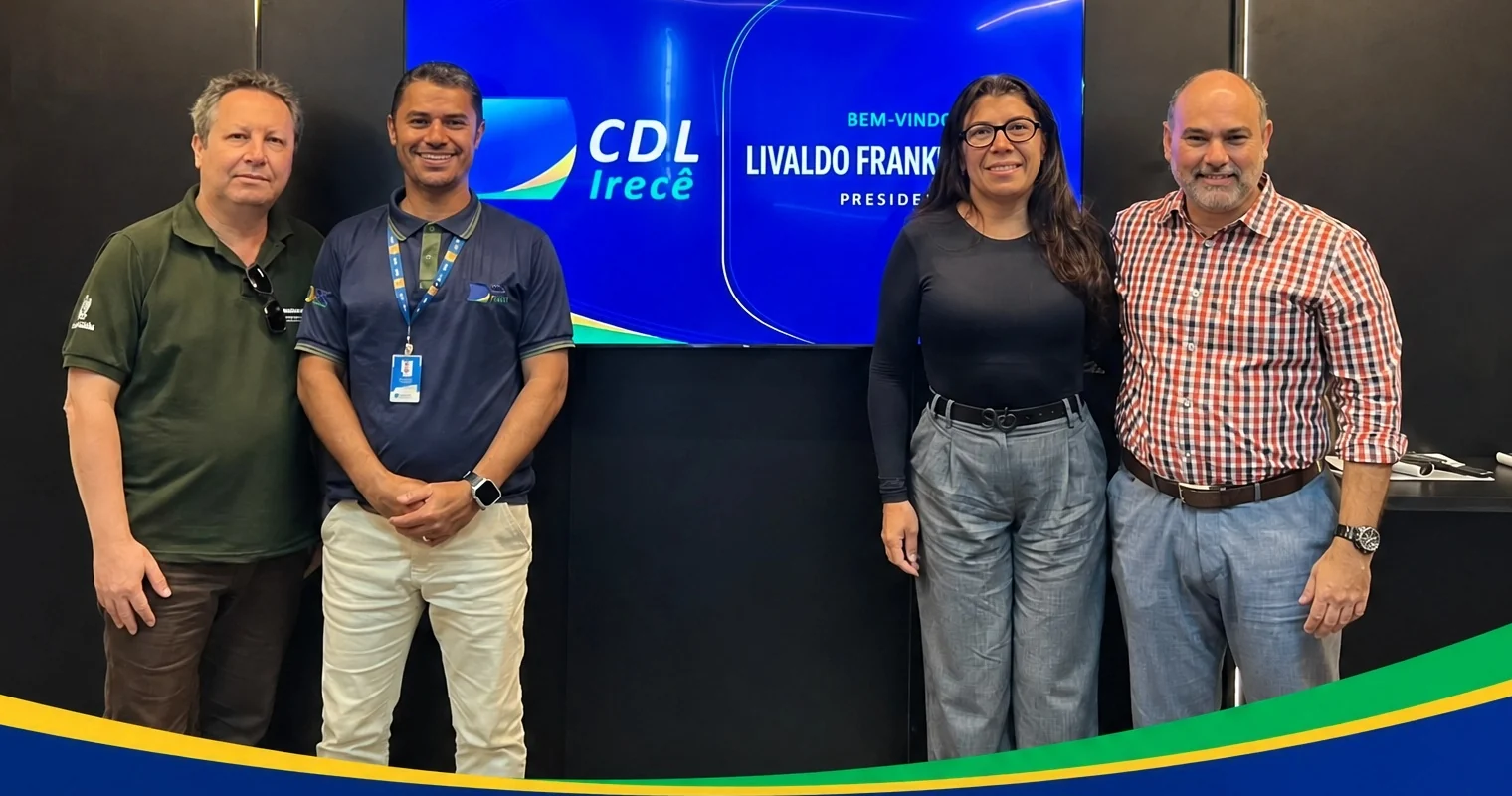 Quatro participantes de um encontro de parceiros diante do painel da CDL Irecê